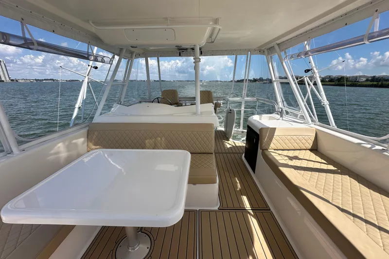 Slide: The Image of 2005 Riviera 47 Open Flybridge interior with seating and table, overlooking calm waters. - 34