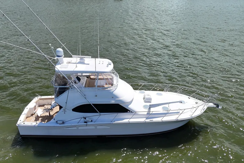 Slide: The Image of 2005 Riviera 47 Open Flybridge yacht on calm water, showcasing sleek design and spacious deck. - 4