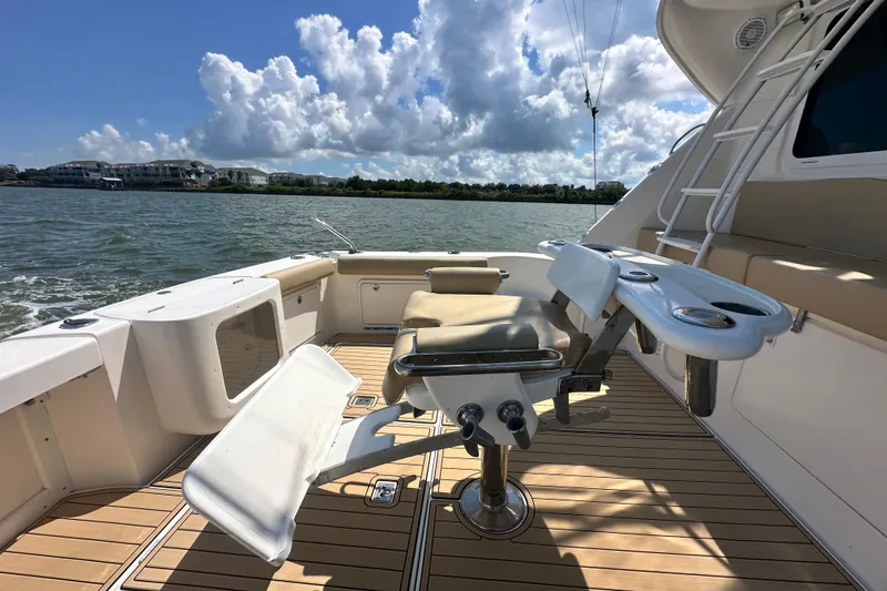Slide: The Image of 2005 Riviera 47 Open Flybridge yacht deck with fishing chair, rod holders, and scenic water view. - 43