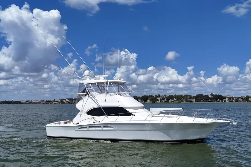 Slide: The Image of 2005 Riviera 47 Open Flybridge yacht on calm water under a blue sky. - 5
