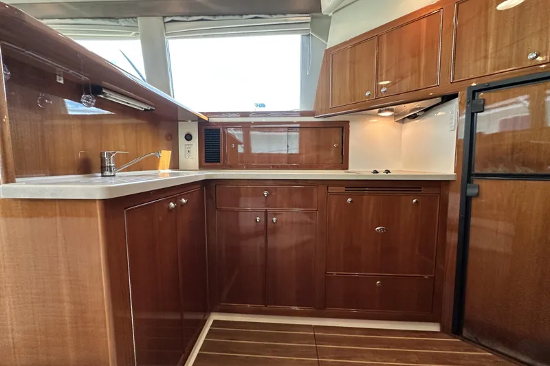 Slide: The Image of Luxurious 2005 Riviera 47 Open Flybridge yacht kitchen with wooden cabinetry and modern appliances. - 92