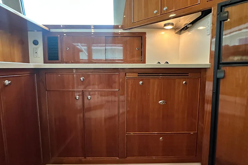 Slide: The Image of 2005 Riviera 47 Open Flybridge yacht kitchen with wooden cabinetry and modern appliances. - 93