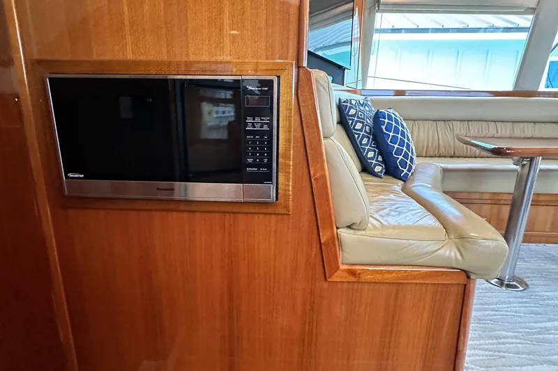 Slide: The Image of 2005 Riviera 47 Open Flybridge interior with microwave, leather seating, and decorative cushions. - 98