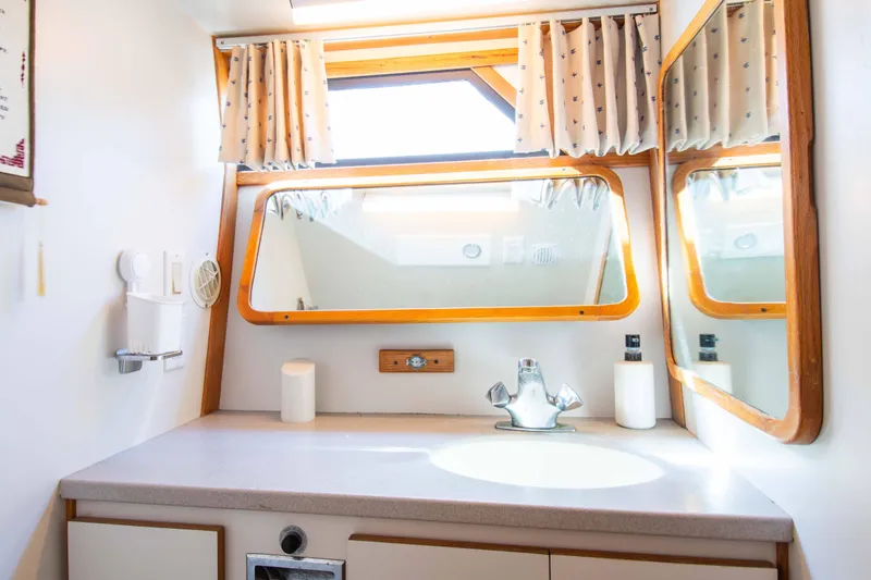 Slide: The Image of 1989 Chris-Craft Catalina bathroom with sink, mirror, and nautical-themed curtains. - 10