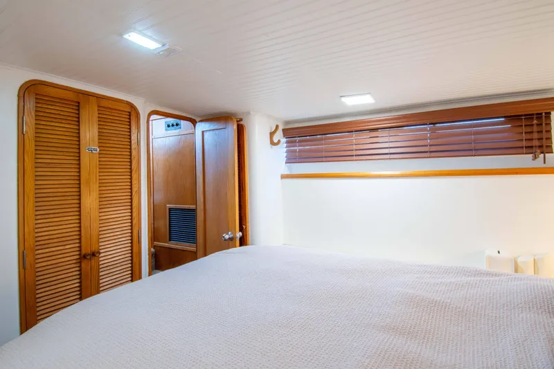 Slide: The Image of 1989 Chris-Craft Catalina cabin interior with wooden closets and blinds, featuring cozy bedding. - 12