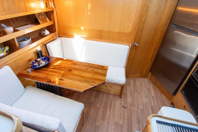 Slide: The Image of 1989 Chris-Craft Catalina interior with wooden dining area and white cushioned seating. - 22