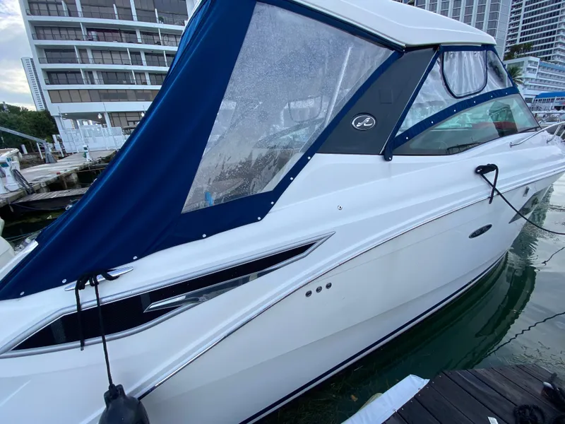 Slide: The Image of 2020 Sea Ray Sundancer 320 OB docked, featuring sleek design and blue canopy. - 11
