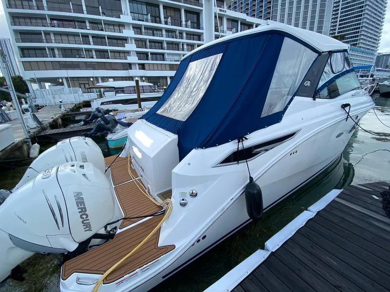 Slide: The Image of 2020 Sea Ray Sundancer 320 OB docked, featuring dual Mercury outboard engines and a blue canopy. - 12