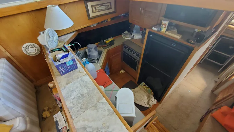 Slide: The Image of 1985 Silverton 40 Aft Cabin interior with kitchen area, appliances, and cluttered countertops. - 12