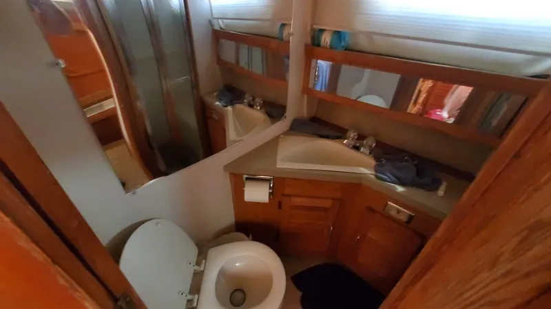 Slide: The Image of 1985 Silverton 40 Aft Cabin bathroom with toilet, sink, and wooden cabinetry. - 8