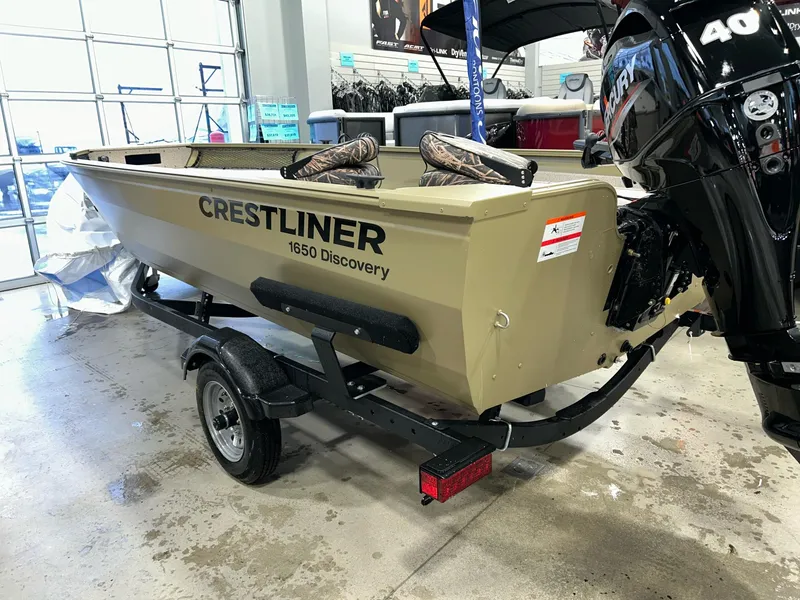 Slide: The Image of 2023 Crestliner 1650 Discovery Tiller boat on trailer in showroom. - 2