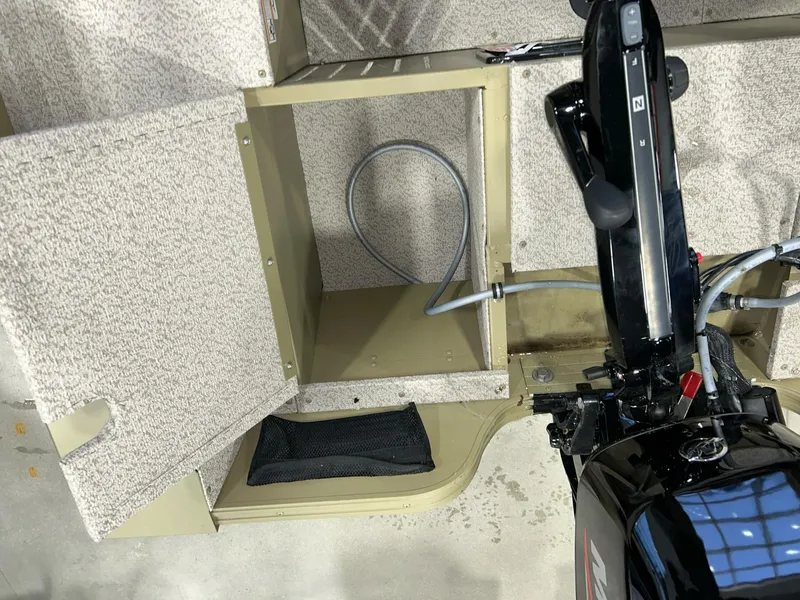 Slide: The Image of 2023 Crestliner 1650 Discovery Tiller boat interior with open storage compartment and motor controls. - 8