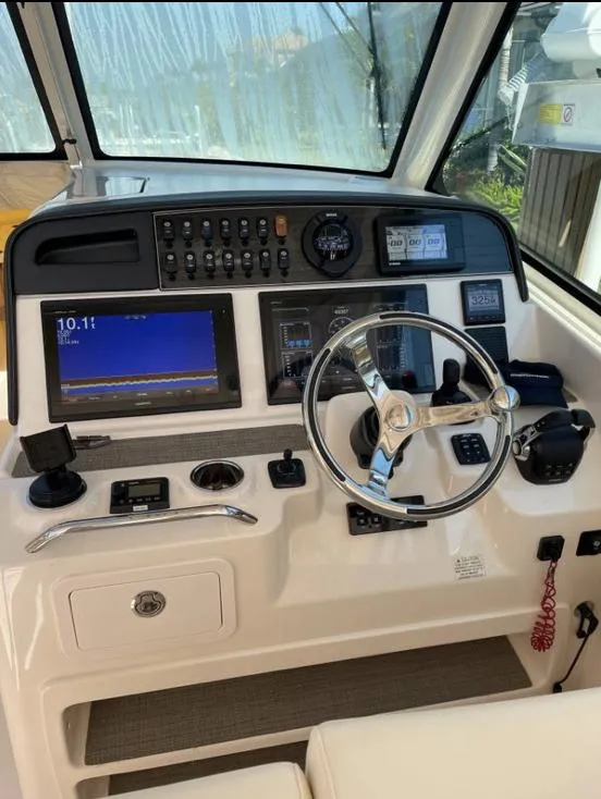 Slide: The Image of 2019 Grady-White Freedom 375 boat dashboard with steering wheel and navigation controls. - 23