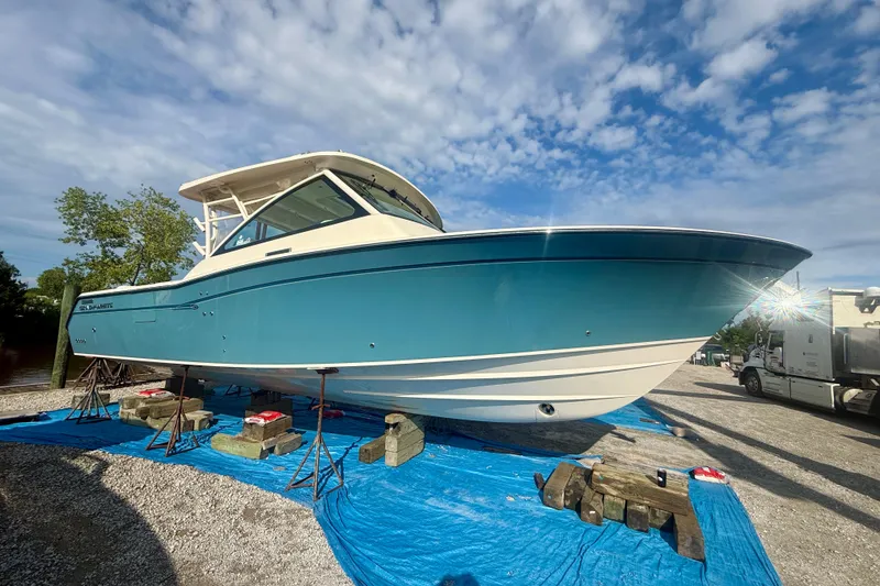 Slide: The Image of 2019 Grady-White Freedom 375 boat on stands, blue hull, sunny day. - 4
