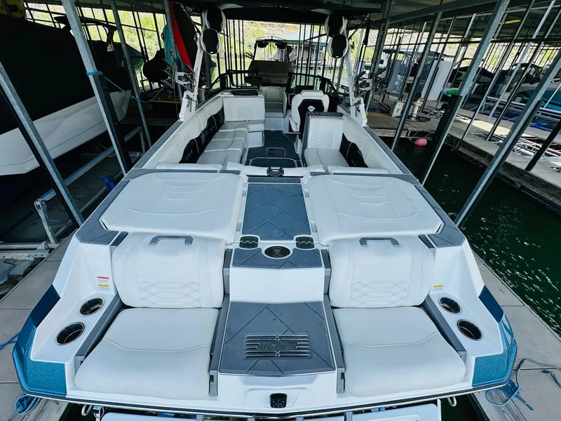 Slide: The Image of 2023 Malibu 25LSV boat interior with spacious seating and modern design in a marina. - 11