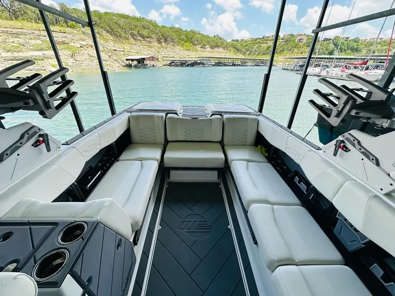 Slide: The Image of Interior of 2023 Malibu 25LSV boat with white seating and scenic lake view. - 17