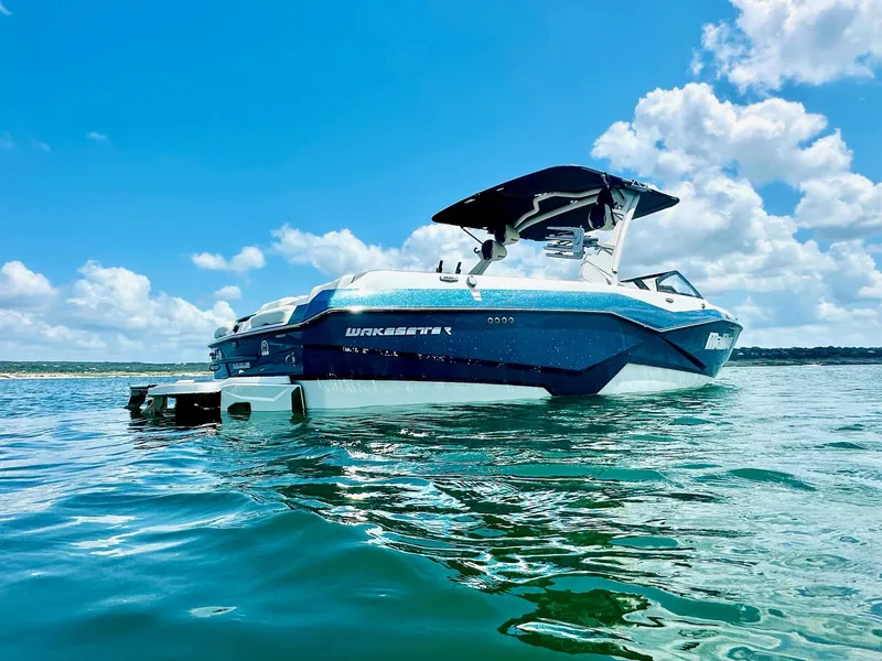 Slide: The Image of 2023 Malibu 25LSV boat on clear blue water under a bright sky. - 2