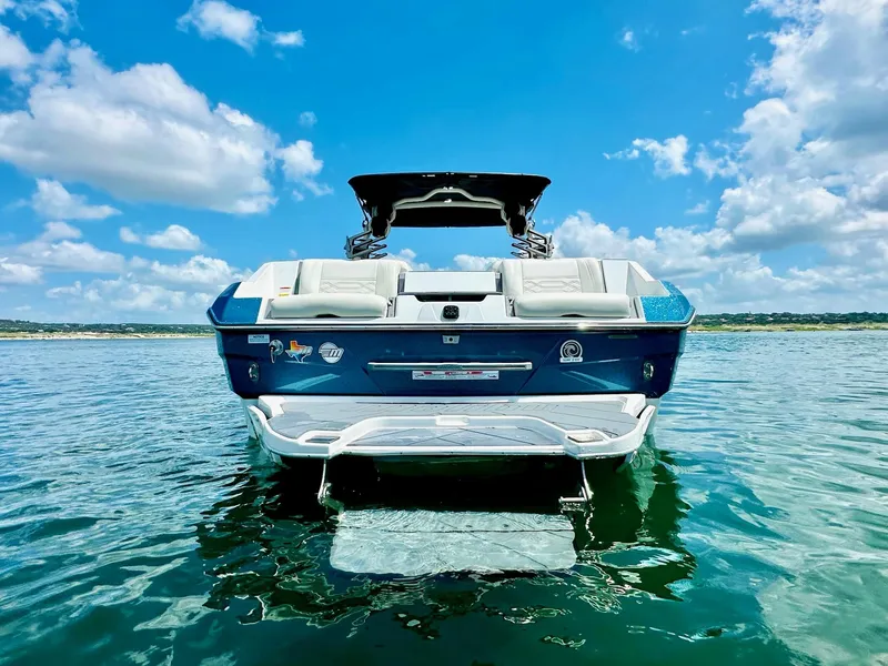 Slide: The Image of 2023 Malibu 25LSV boat on water under a bright blue sky. - 3