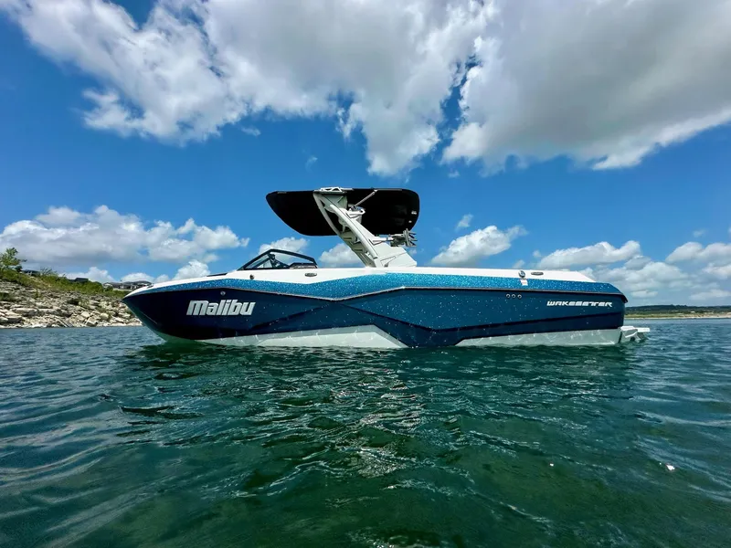 Slide: The Image of 2023 Malibu 25LSV boat on water under blue sky with clouds. - 4