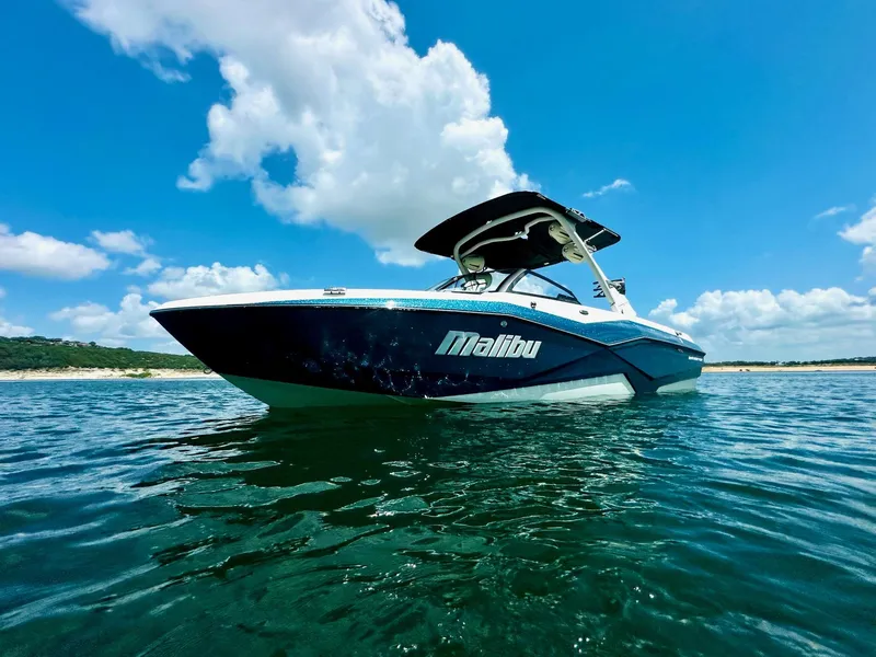 Slide: The Image of 2023 Malibu 25LSV boat on clear water under a bright blue sky. - 5