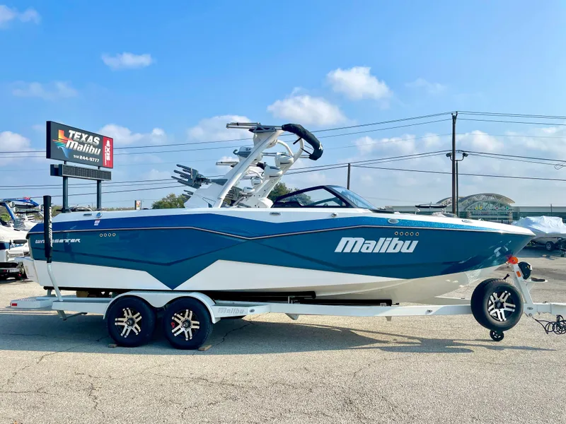 Slide: The Image of 2023 Malibu 25LSV boat on trailer at Texas Malibu dealership under clear blue sky. - 6