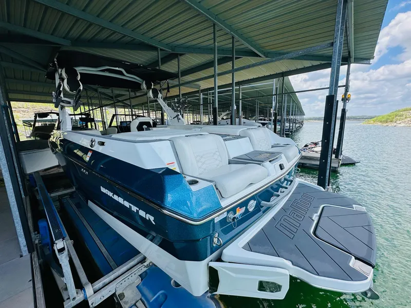 Slide: The Image of 2023 Malibu 25LSV boat docked in a marina, showcasing sleek design and spacious seating. - 8