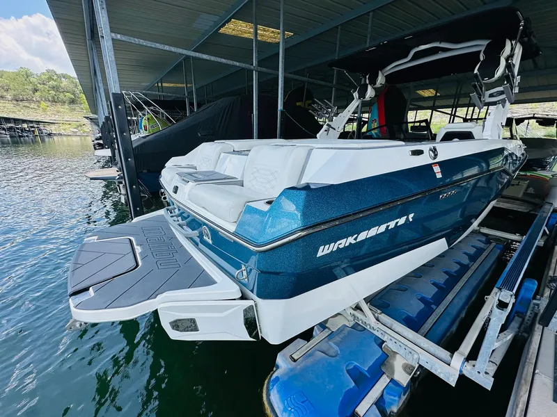 Slide: The Image of 2023 Malibu 25LSV boat docked, featuring sleek design and modern amenities. - 9