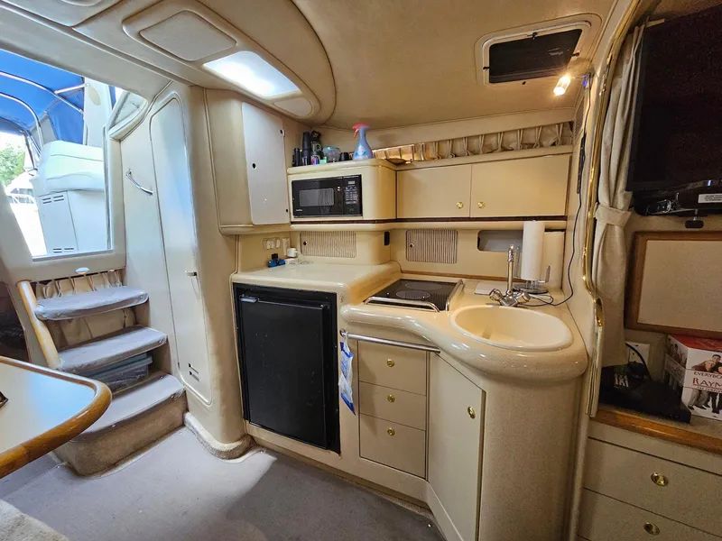 Slide: The Image of Interior of a 1998 Sea Ray 330 Sundancer boat featuring a compact kitchen area. - 10