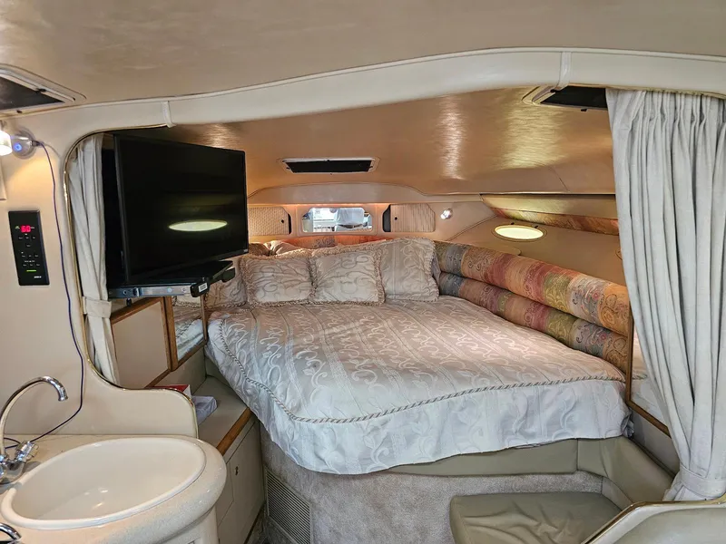 Slide: The Image of 1998 Sea Ray 330 Sundancer cabin with bed, TV, and sink. Luxurious interior design. - 15