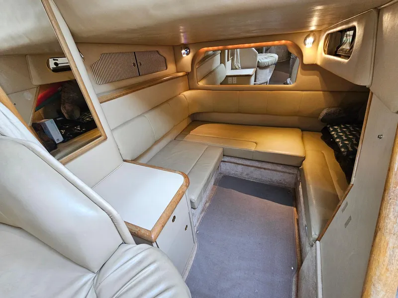 Slide: The Image of Interior of 1998 Sea Ray 330 Sundancer, featuring beige leather seating and wood accents. - 16