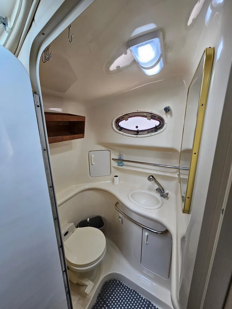 Slide: The Image of 1998 Sea Ray 330 Sundancer bathroom with sink, toilet, and porthole window. - 17