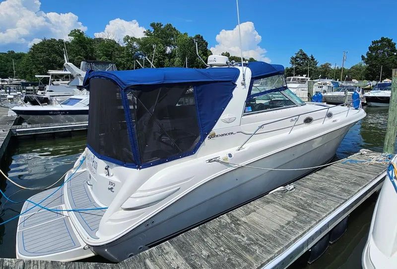 Slide: The Image of 1998 Sea Ray 330 Sundancer docked at marina, featuring blue canopy and sleek design. - 2