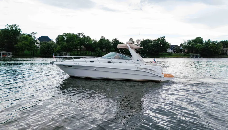 The Image of 2000 Sea Ray 340 Sundancer yacht cruising on a serene lake with lush greenery. - 0