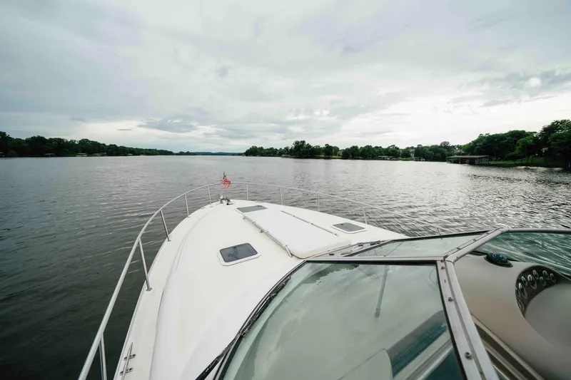Slide: The Image of 2000 Sea Ray 340 Sundancer cruising on a serene lake under a cloudy sky. - 10