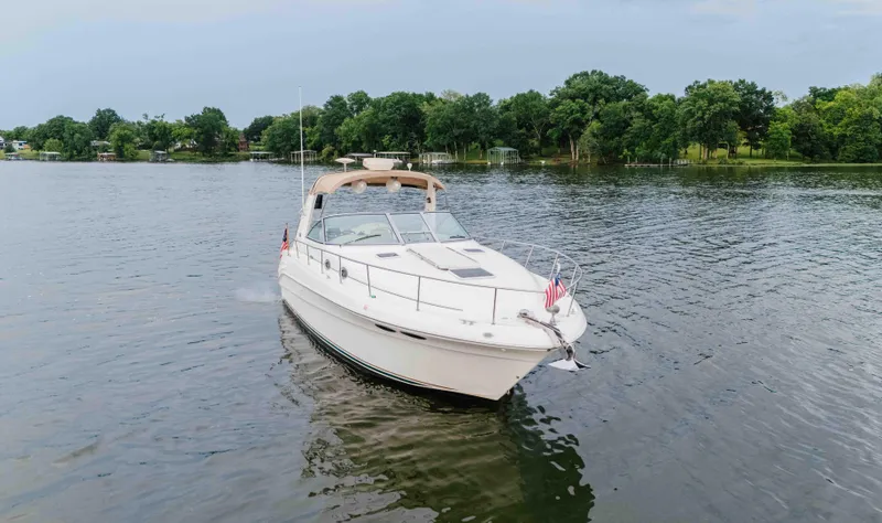 Slide: The Image of 2000 Sea Ray 340 Sundancer cruising on a serene lake with lush green shoreline. - 3