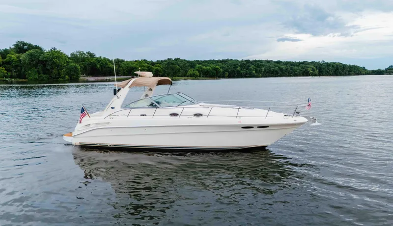 Slide: The Image of 2000 Sea Ray 340 Sundancer yacht cruising on a serene lake with lush green shoreline. - 5