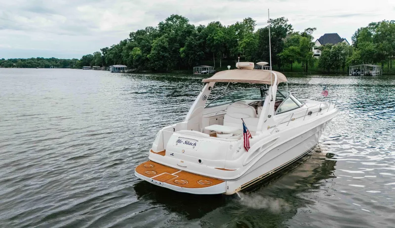 Slide: The Image of 2000 Sea Ray 340 Sundancer yacht on a serene lake with lush green shoreline. - 6