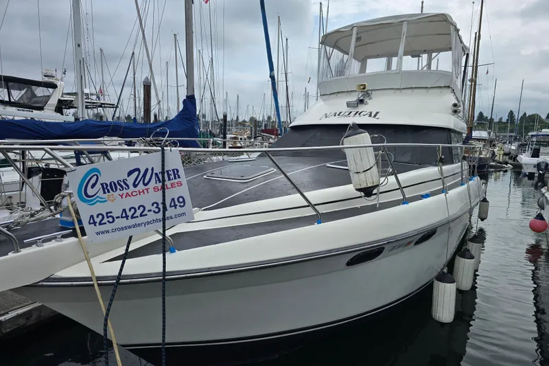 Slide: The Image of 1990 Silverton 37 Convertible yacht docked, featuring Cross Water Yacht Sales sign. - 2