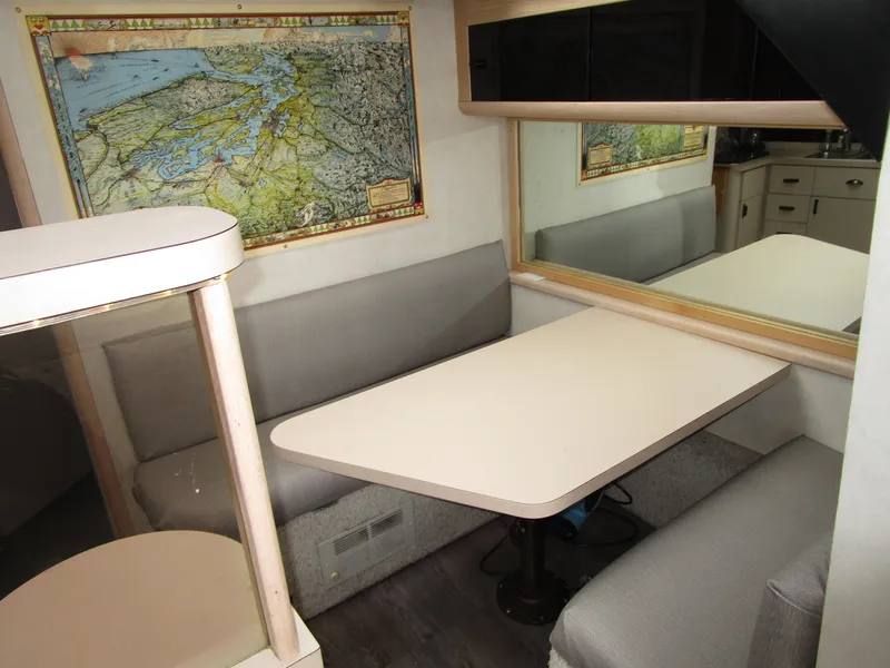 Slide: The Image of 1990 Silverton 37 Convertible interior with dining area, map decor, and cushioned seating. - 27