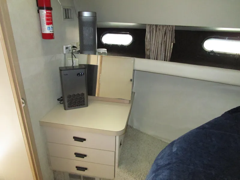 Slide: The Image of 1990 Silverton 37 Convertible cabin interior with desk, drawers, and porthole windows. - 33