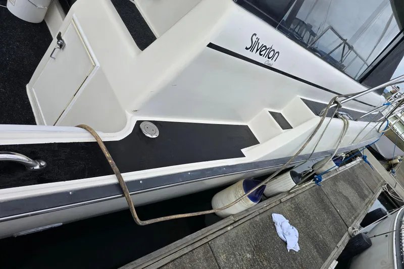 Slide: The Image of 1990 Silverton 37 Convertible yacht docked, showing side view with ropes and fenders. - 38