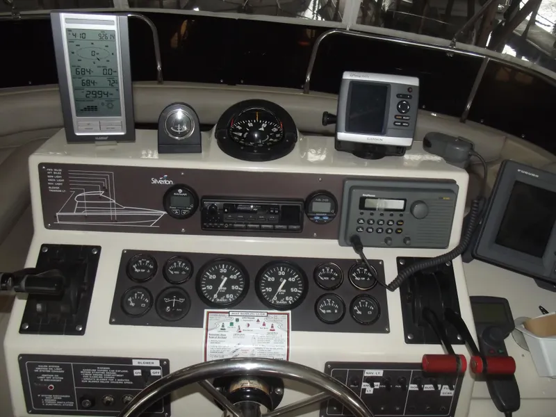 Slide: The Image of 1990 Silverton 37 Convertible boat dashboard with gauges, navigation equipment, and steering wheel. - 5