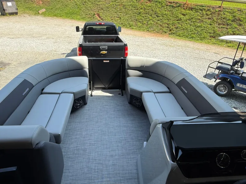 Slide: The Image of 2025 Viaggio Lago V-U pontoon boat interior with gray seating and a truck in the background. - 14