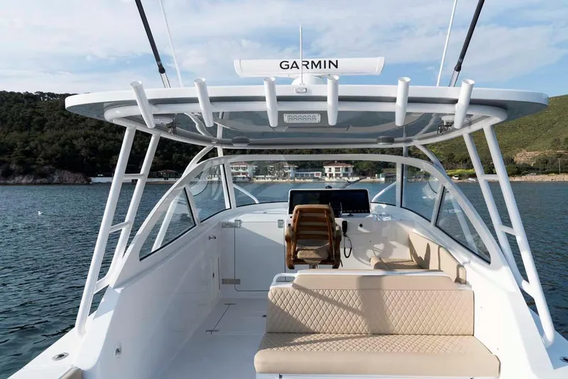 Slide: The Image of 2025 Vicem Express boat interior with Garmin equipment, featuring seating and helm, on calm water. - 7
