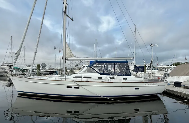 The Image of 2003 Beneteau Oceanis 42CC sailboat docked in a marina, reflecting on calm water. - 0