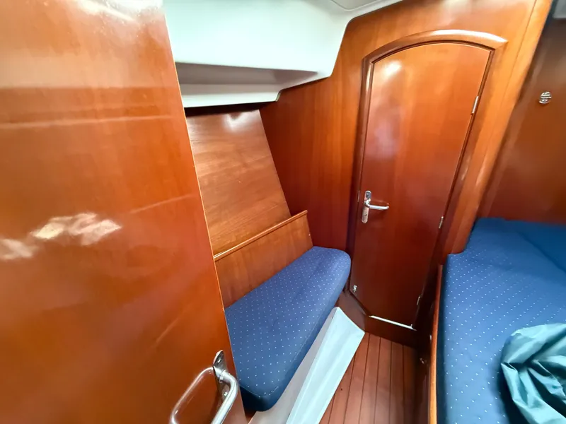 Slide: The Image of Interior of 2003 Beneteau Oceanis 42CC yacht, featuring wooden paneling and cozy seating. - 27