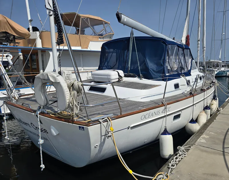 Slide: The Image of 2003 Beneteau Oceanis 42CC sailboat docked at marina, featuring blue canopy and fenders. - 9