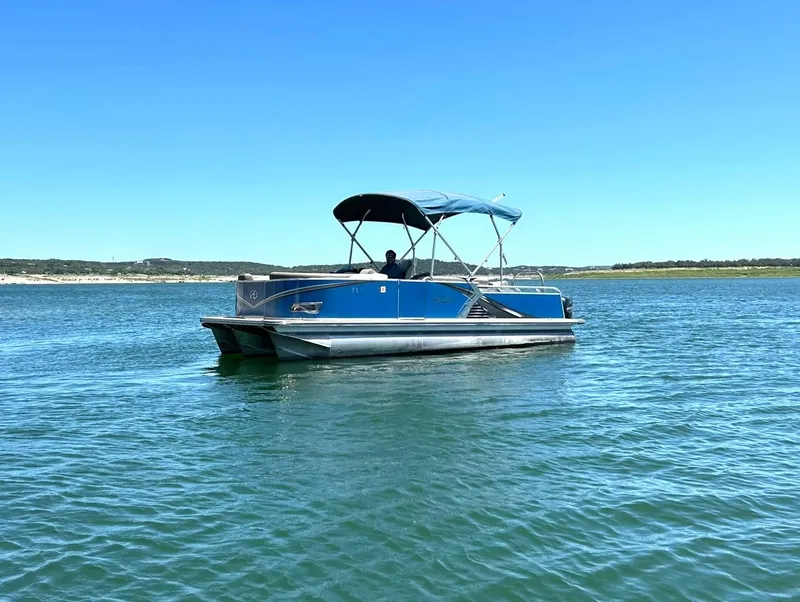 Slide: The Image of 2022 Avalon 24 LSZ VRB-3 pontoon boat on a calm lake under clear blue skies. - 2