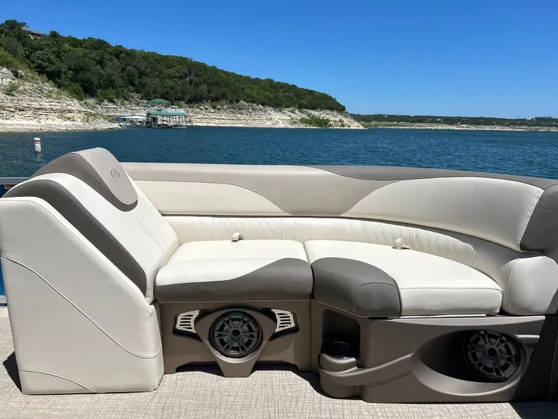 Slide: The Image of 2022 Avalon 24 LSZ VRB-3 pontoon boat interior with plush seating, on a scenic lake. - 22