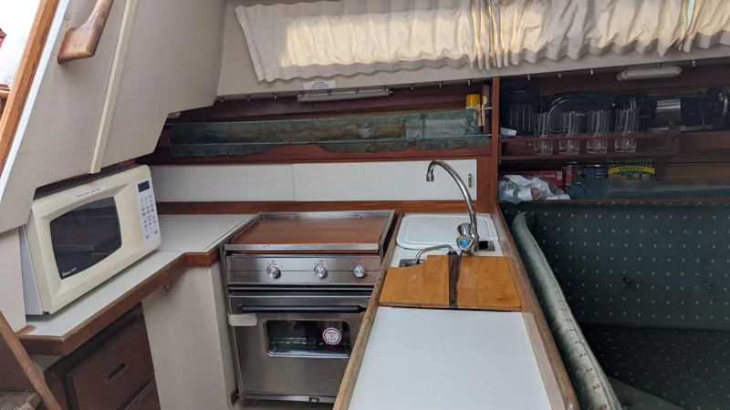 Slide: The Image of Interior of 1988 Catalina 30 MkII sailboat kitchen with stove, sink, and microwave. - 22